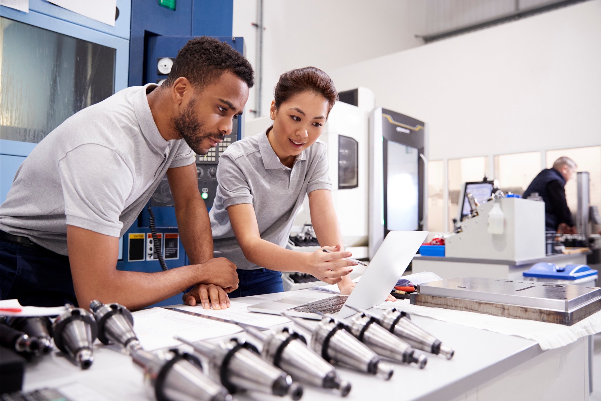 CNC engineer technicians collaborating in machine shop